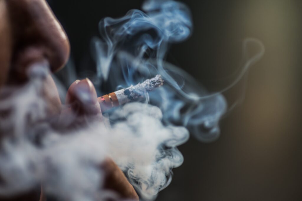 Closeup shot of a person puffing on a cigarette surrounded with smoke Les causes de la calvitie masculine gros plan personne soufflant cigarette entouree fumee
